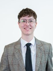 A smiling person with glasses and short dark hair.