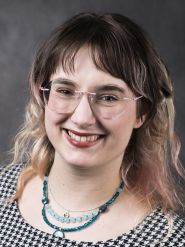 A smiling woman with glasses and two-toned hair.