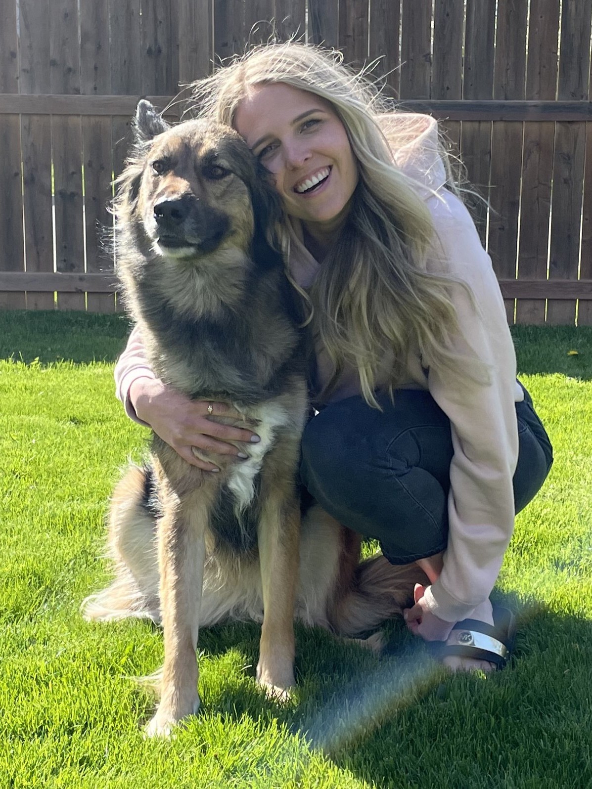 A smiling woman with long blond hair, posed with a large dog.
