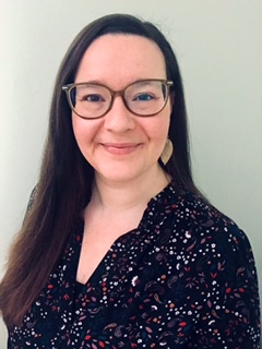 A smiling woman with glasses and long dark hair.